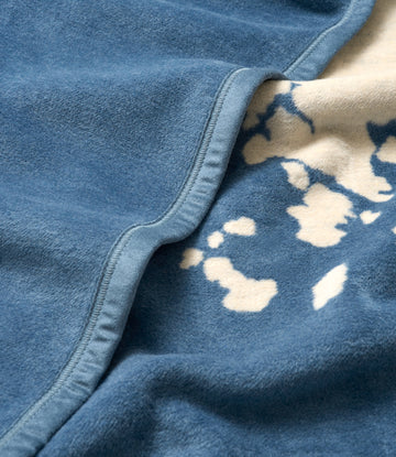 Blue fleece blanket with cream-colored Maine state map pattern and bound edge detail.3