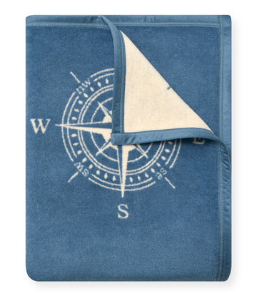 Blue blanket with cream compass rose design and beige reverse side, partially folded to show both sides.4