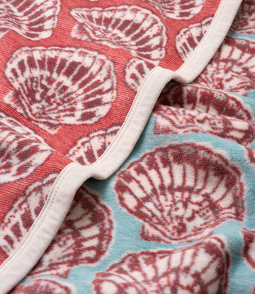 Folded blanket with red and blue sections featuring white shell patterns and white binding along the edge.4