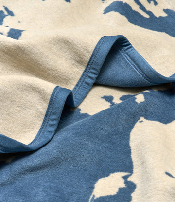 Cream and blue wool blanket with map pattern and sewn binding edge detail.3