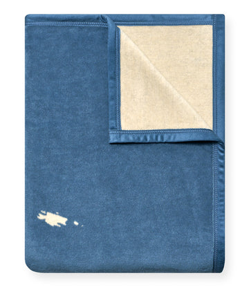 Blue blanket with cream-colored San Juan Islands map design and cream backing, partially folded.4
