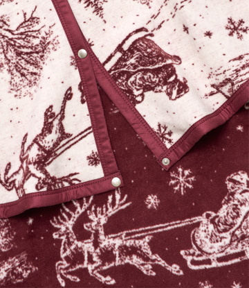 Burgundy and cream tree skirt with toile pattern featuring Santa, reindeer, and snowflakes, secured with pearl button straps.4