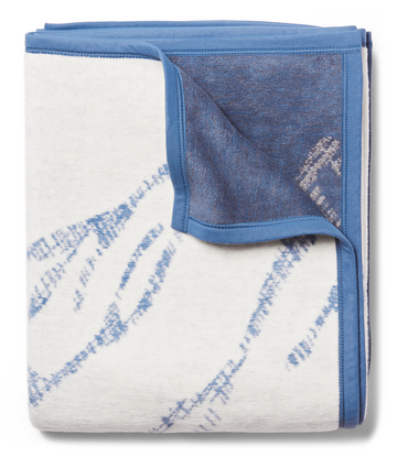 Blue and cream blanket with ski track pattern and blue binding edges, folded to show both sides.7