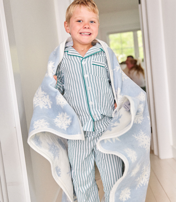 Light blue blanket with white snowflake pattern wrapped around child wearing striped pajamas.4