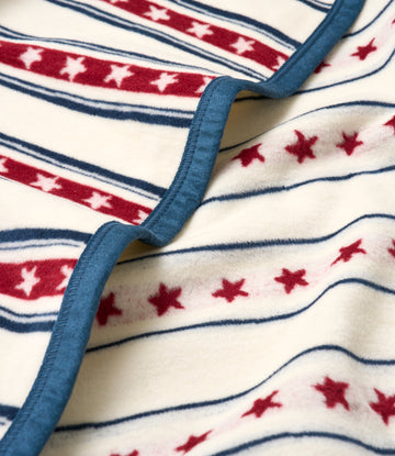 Cream blanket with red stars and navy stripes, showing blue binding edge detail.5