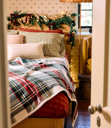 Stewart plaid blanket with red, navy, and yellow tartan pattern draped across a bed.2