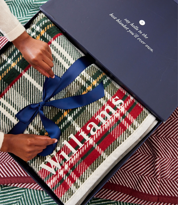 Stewart plaid blanket in green, red, and cream with white text, tied with blue ribbon in gift box.5