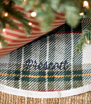 Red, green, and navy plaid tree skirt with "Prescott" text and gold trim detail around base.3
