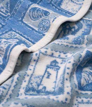 Blue and white blanket with circular stamp and scenic patterns, white binding along edges.4