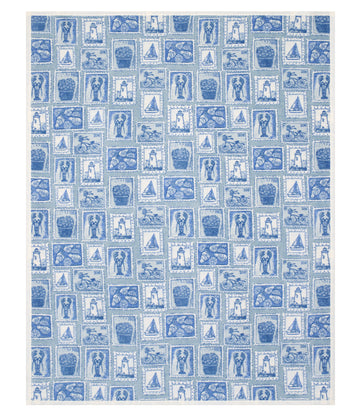 Blue and white blanket with an all-over stamp print featuring lighthouses, sailboats, baskets, and decorative patterns.2