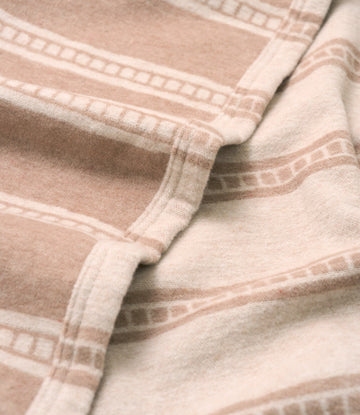 Tan and cream lightweight blanket with geometric tile stripe pattern and stitched details.4