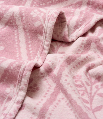 Pink and cream floral patterned lightweight blanket with woven texture and sewn binding.5