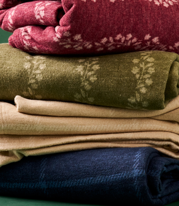 Stacked folded blankets in burgundy, olive, tan, and navy with windowpane woven pattern detail.4