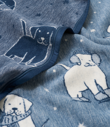 Blue knit blanket with white and dark navy puppy faces and snowflake pattern throughout.4