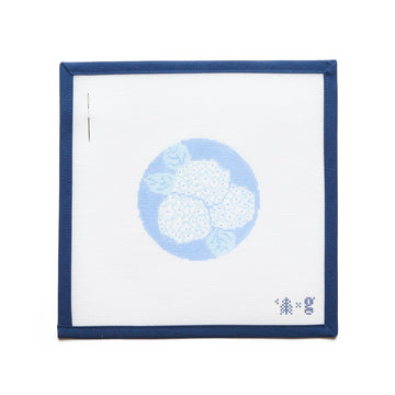 Needlepoint canvas with white hydrangea flowers on light blue circular background, framed in navy blue border.6